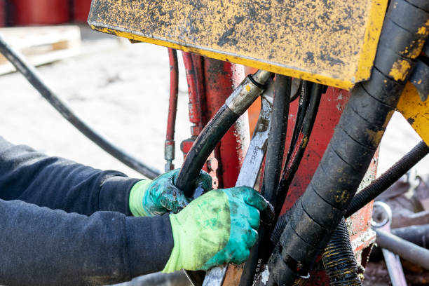 Worker is repairing hydraulic pipes of working machine. Hydraulic machines use liquid fluid power to perform work. Heavy construction vehicles are a common example.